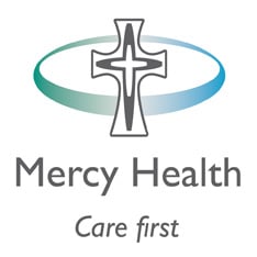 Mercy Health Care First logo featuring a cross within a circle on a white background, symbolizing faith-based compassion in healthcare. The text "Mercy Health" and "Care First" provide context and identification for the logo. SCS Group supports Mercy Health Care First in their ministry of compassionate healthcare.