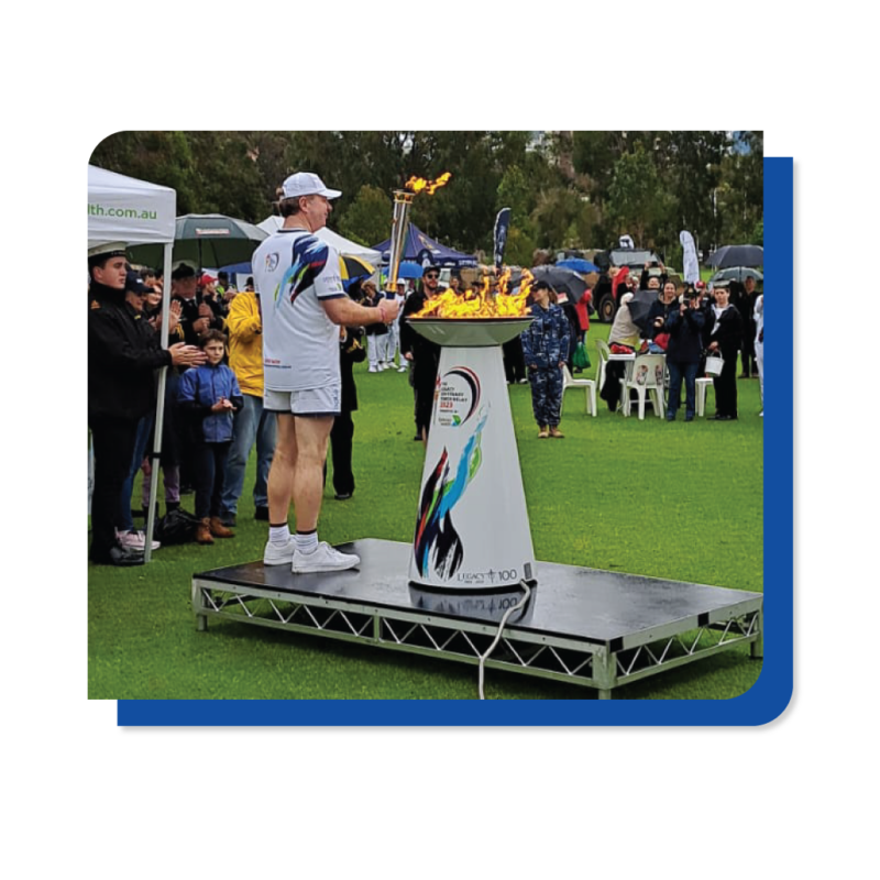 A man stands confidently on a stage, holding a torch aloft, symbolizing inspiration and leadership.