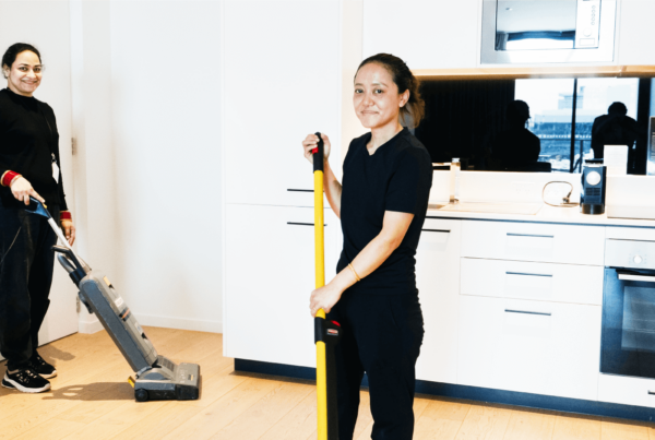 Two women efficiently vacuuming a hotel kitchen, ensuring a clean and tidy environment for guests and staff.